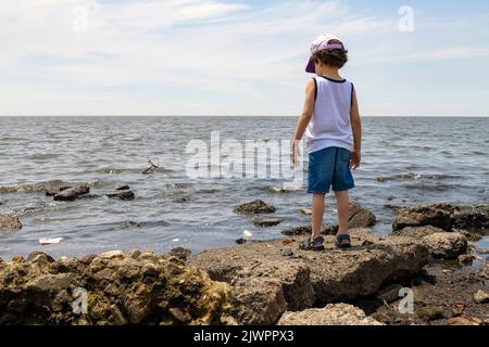 petit garçon regardant la rivière polluée de la rive, concept environnemental Banque D'Images