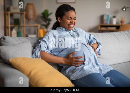 Femme noire enceinte souffrant de douleur ayant un spasme douloureux à l'intérieur Banque D'Images