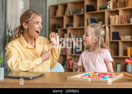 Femme orthophoniste professionnelle traitant les problèmes et les obstacles de la fille, mignon enfant apprendre des lettres avec le tuteur Banque D'Images