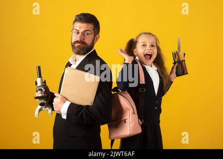 Retour à l'école, fille étudiante avec uniforme. Gai souriant petite fille dans l'uniforme de l'école avoir du plaisir en studio. Portrait de l'élève heureux excité émerveillé Banque D'Images