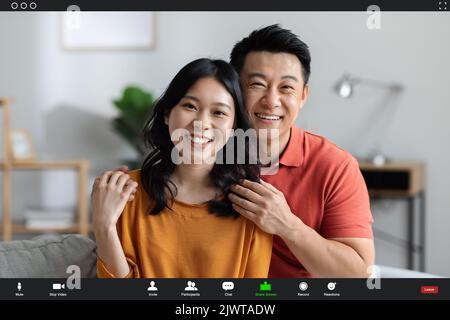 Couple coréen joyeux ayant la vidéo conférence avec des amis, capture d'écran Banque D'Images