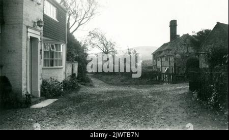 1950s. Un hameau pittoresque et pittoresque de Cornwall, en Angleterre. La vue montre une petite maison avec une baie vitrée et un ancien cottage à pans de bois entouré d'une clôture de piquetage. Banque D'Images