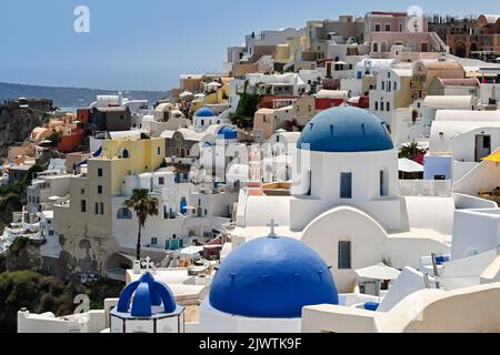 Oia, Santorini, Grèce - juin 2022 : bâtiments traditionnels blanchis à la chaux avec dômes bleus surplombant la mer à Oia Banque D'Images