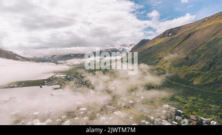 Brouillard matinal au-dessus d'une petite ville au milieu des montagnes dans le nord de l'Islande - Siglufjordur Banque D'Images