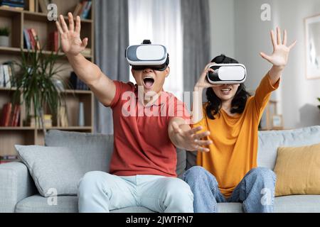 Excitée drôle couple coréen jouant des jeux vidéo, en utilisant des lunettes VR Banque D'Images