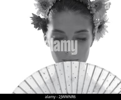 Gris ne peut pas tuer la beauté d'été. Photo en noir et blanc d'une belle jeune femme portant une couronne de fleurs tout en tenant un ventilateur devant son visage. Banque D'Images