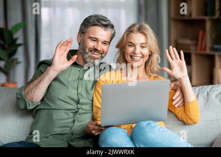 Joyeux couple d'âge moyen effectuant un appel vidéo avec un ordinateur portable à la maison Banque D'Images