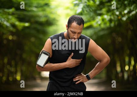 Homme noir musclé avec douleur cardiaque, entraînement à l'extérieur Banque D'Images