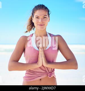 Trouver la paix intérieure une pose à la fois. Une jeune femme faisant du yoga à la plage. Banque D'Images