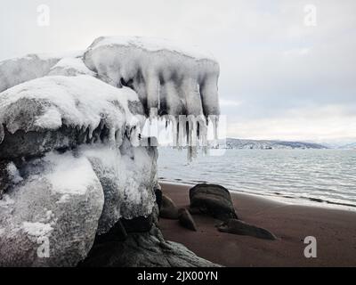 Rochers couverts de glace et de glace sur la plage de sable noir Banque D'Images