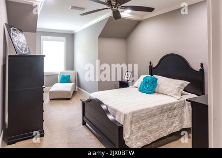 Cette chambre spacieuse dispose d''un lit en bois sombre et d''une commode ou d''une commode ainsi que d''un ventilateur et d''une chaise à mâche Banque D'Images