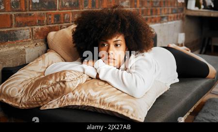 Femme africaine triste, fatiguée et déprimée pensant à l'épuisement, l'anxiété et la dépression sur le canapé dans le salon à la maison. Fille en santé mentale Banque D'Images