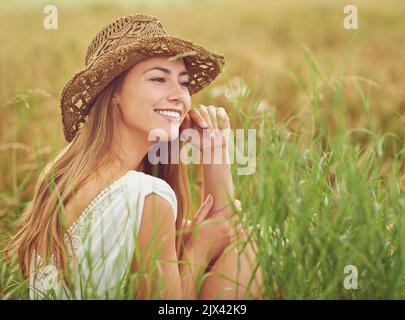 C'est le silence des choses qui grandissent. Une jeune femme assise dans un champ à la campagne. Banque D'Images