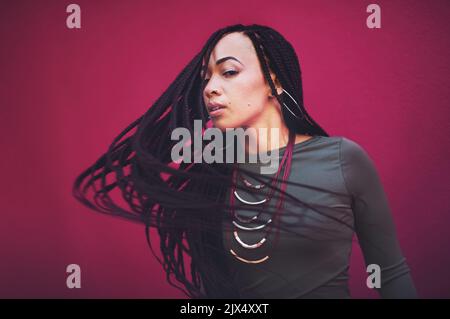 Libre d'être moi. Une jeune femme avec des tresses posant sur un fond rose. Banque D'Images