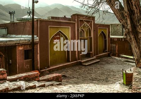 Abyane, Iran, 17 février 2022: Une petite mosquée en argile rouge avec une belle porte double sculptée dans le village d'Abyaneh au carrefour de St étroit Banque D'Images