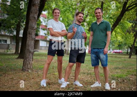 Trois beaux jeunes hommes s'amusent dans un parc Banque D'Images