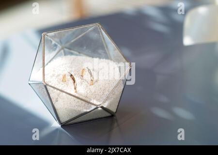 Une paire de magnifiques anneaux de mariage dans un support en verre moderne. Mariage, cérémonie. Mise au point sélective douce. Banque D'Images