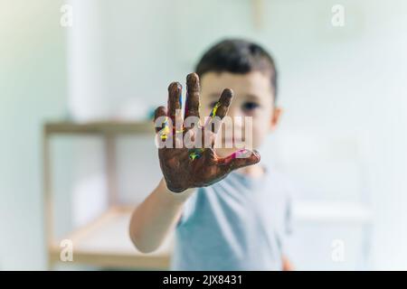 Peinture de film adhésif. Les tout-petits peignent avec une éponge, des pinceaux et des peintures sur un film adhésif enroulé autour de l'étagère en bois. Un enseignant les aidant. Activité créative pour les enfants développement des compétences sensorielles à la maternelle. Photo de haute qualité Banque D'Images