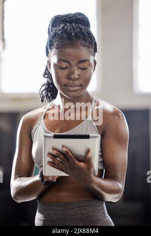 Entraîneur personnel avec tablette numérique, technologie mobile de bien-être dans la salle de gym et femme noire exercice dans la salle de fitness. Athlète sportif en ligne, entraîneur d'entraînement Banque D'Images