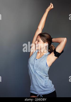 Il est agréable d'être en forme. Photo en studio d'une jeune femme sportive se posant sur un fond gris. Banque D'Images