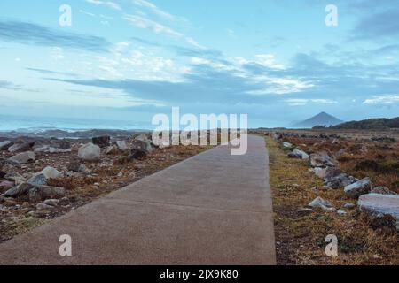 Vue aérienne de la route avec pierres et montagne sur la côte atlantique de l'océan. Pierres et rochers avec mousse sur la route le long de l'océan. Côte avec brume matinale. Banque D'Images