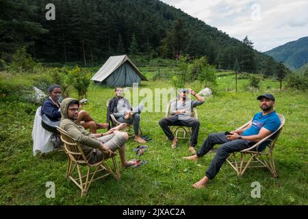 17 septembre 2021 Himalaya Uttarakhand Inde. Un groupe de campeurs se détendant ensemble sur un camping entouré de montagnes et de forêt de déodar. Banque D'Images