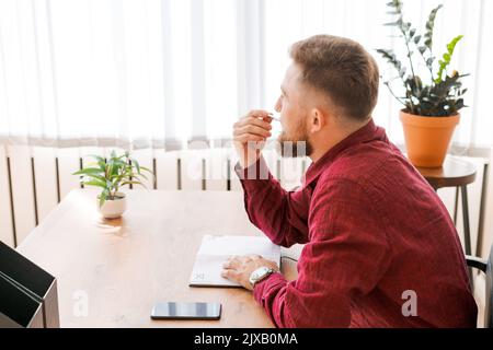 Homme d'affaires, directeur exécutif remplissant le bloc-notes papier, planification d'affaires de la journée de travail, assis à table dans le bureau moderne, homme caucasien barbu dans les vêtements d'affaires Banque D'Images