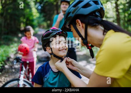 Une jeune famille avec de petits enfants se tient debout avec des vélos dans la nature. Banque D'Images