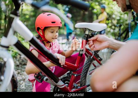 Une jeune famille avec de petits enfants se tient debout avec des vélos dans la nature. Banque D'Images