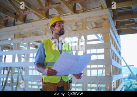 Ingénieur de construction ou architecte avec des plans de visite et de damier site de construction écologique de la maison de cadre en bois Banque D'Images