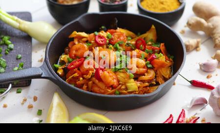 Crevettes frites sur une poêle à repasser avec des légumes et des herbes fraîches Banque D'Images