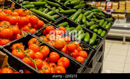 Vitrine avec une gamme de fruits au supermarché. Vente de nourriture. Vente au détail. Les tomates fraîches et les concombres sont stockés sur des étagères. Légumes mûrs et sains. Bio produits alimentaires locaux concept d'achats de supermarchés d'aliments diététiques avec des vitamines et des fibres. Banque D'Images