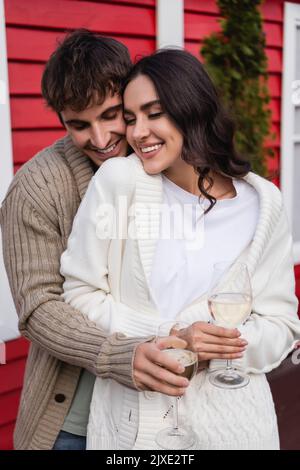 Couple souriant dans cardigans tenant des verres de vin à l'extérieur, image de stock Banque D'Images