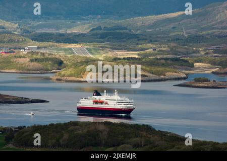 Hurtigrluten navire Kong Harald passant le dôme de granit de Torghatten dans le centre de la Norvège tout en quittant Brønnøysund. Banque D'Images