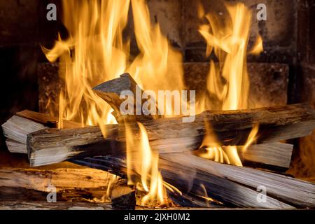 Le feu brûle dans le four à pizza au feu de bois avec une flamme derrière Banque D'Images