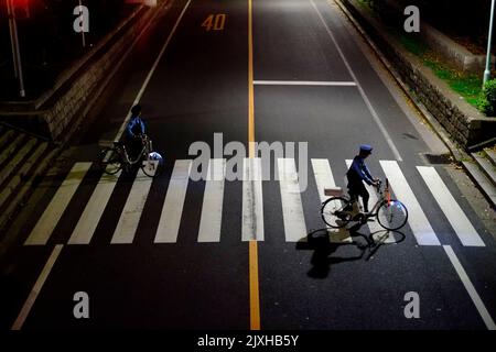 Un couple de la police japonaise sur des vélos traversant la traversée de la traversée de nuit Banque D'Images