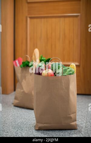 Des sacs de shopping de nourriture sont à la porte de la maison ou de l'appartement.Livraison de légumes et de fruits pendant la quarantaine et l'auto-isolement. Banque D'Images