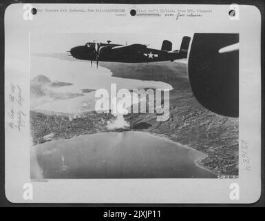 Les bombardiers nord-américains B-25 Mitchell de l'AAF 13th sont illustrés ici, se dévalant de la zone d'approvisionnement de Rataval, en Nouvelle-Bretagne, après avoir déposé leurs bombes sur cette cible pour la journée. Un grand feu peut être vu sur la rive de la baie de Talisli Banque D'Images