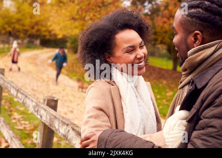 Famille souriante à pied dans la campagne penchée contre Fence Banque D'Images