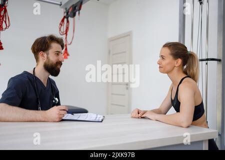 Physiothérapeute médecin consultant une jeune femme athlétique dans une clinique de réadaptation Banque D'Images