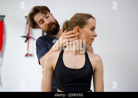 Thérapeute manuel masculin ciblé tournant la tête du patient féminin pour vérifier son cou blessé. Concept d'exercices avec le diagnostic des maladies de la soucoupe Banque D'Images