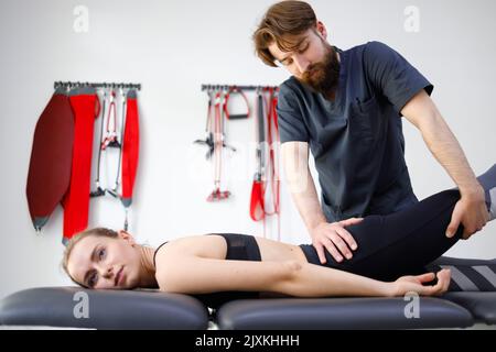 Le massage et le pétrissage de la jambe d'une patiente par un physiothérapeute fournissent des soins médicaux pour les ligaments tensionnés. Femme en clinique de réadaptation Banque D'Images