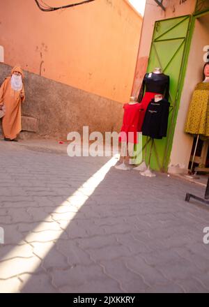 Femme locale à l'extérieur de la boutique de vêtements à Marrakech, Maroc Banque D'Images