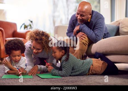 Grands-parents à la maison avec petits-enfants dessin de photos dans le salon ensemble Banque D'Images