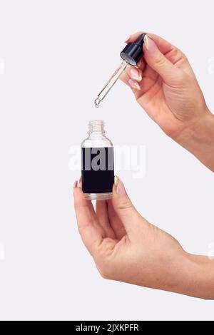 Gros plan Studio prise de vue d'une femme tenant une bouteille d'huile essentielle ou de cannabis avec pipette Banque D'Images