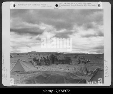 Les membres du 94th Fighter Squadron, 1st Fighter Group, s'assoient à l'extérieur de leurs tentes et discutent des événements de la journée à leur base aérienne en Sardaigne. Banque D'Images