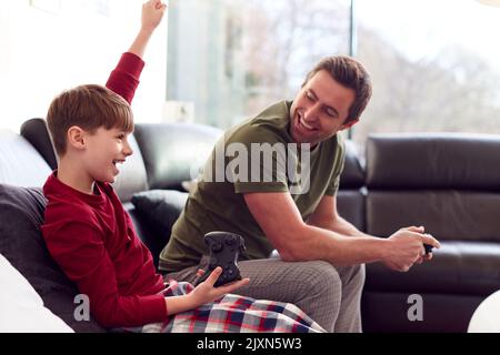 Garçon en pyjama portant un casque de réalité virtuelle jouant à un jeu d'ordinateur à la maison Banque D'Images