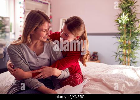 Fille adolescente portant un pyjama enserrant la mère dans la chambre Banque D'Images