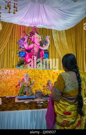 Une femme priant devant une belle idole de Lord Ganesha à un mandal à Mumbai pour le festival indien de Ganesh Chaturthi Banque D'Images