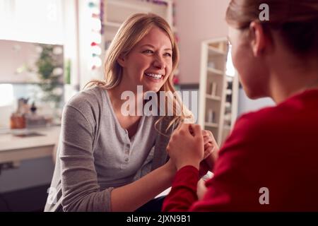 Fille adolescente portant un pyjama assis sur le lit parlant à la mère dans la chambre Banque D'Images